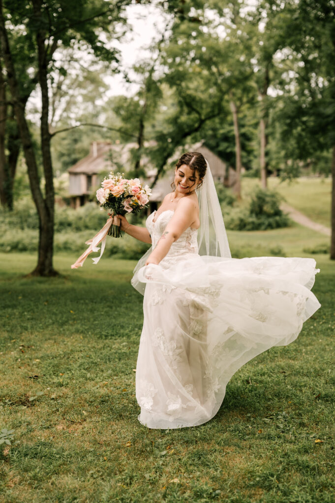 The bride smiling as she twirls in her dress in the grass at Waterloo Village.