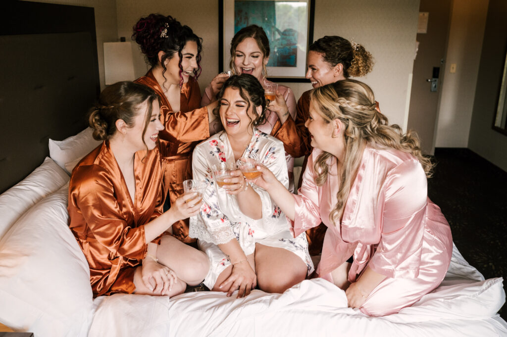 The bride and bridesmaids making a toast as they smile and laugh.