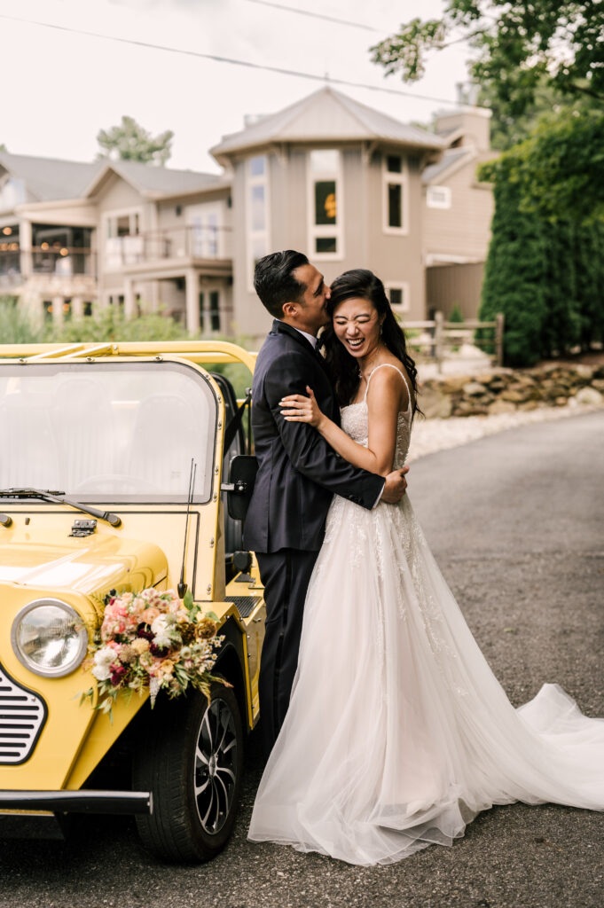 The bride and groom embracing next to the Moke as the groom kisses her head at Rock Island Lake Club.