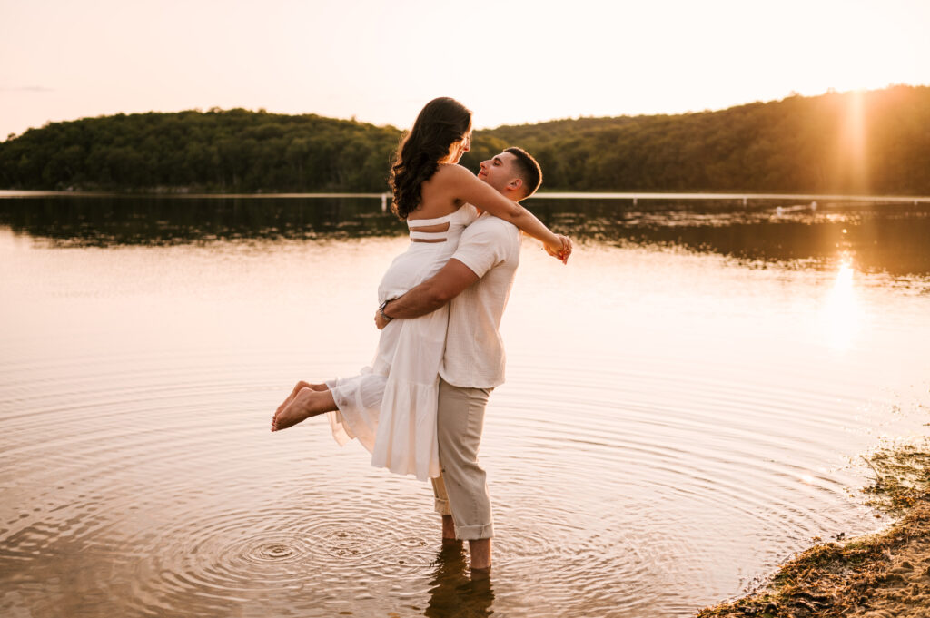 The groom to be picking up his fiancé as they stand in the lake at Wawayanda State Park.