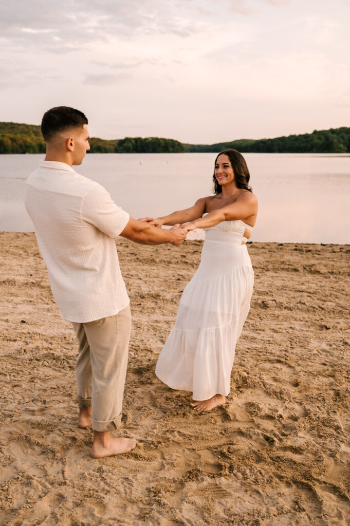 The newly engaged couple spinning and dancing on the shore of the lake at Wawayanda State Park.
