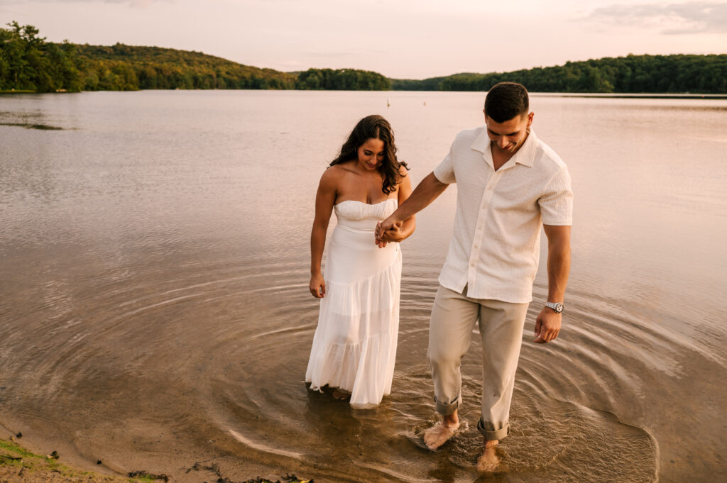 The new engaged couple holding hands as they walk out of the lake at Wawayanda State Park.