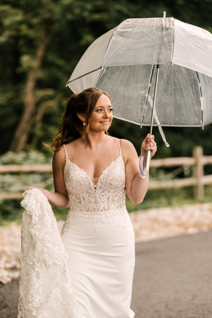 The bride smiling and looking off to the side as she holds an umbrella at Rock Island Lake Club.