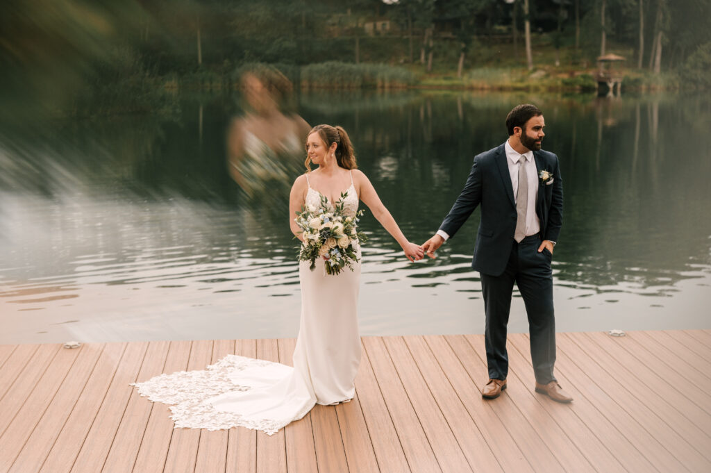 The couple holding hands and looking in opposite directions on the dock at Rock Island Lake Club.