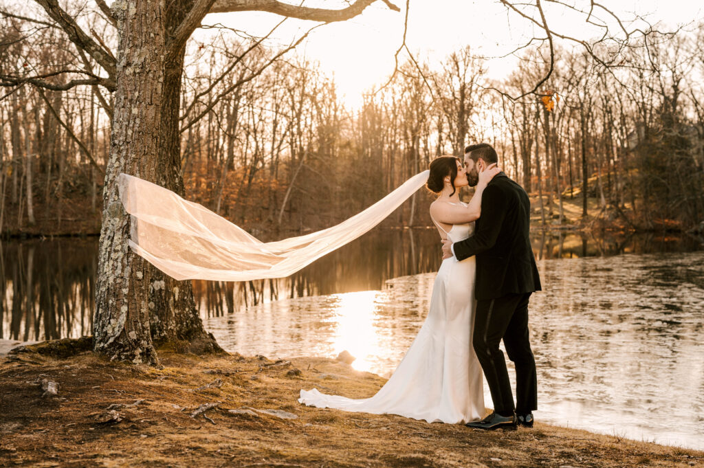bride and groom kiss and veil toss at sunset at Perona Point at Perona Farms