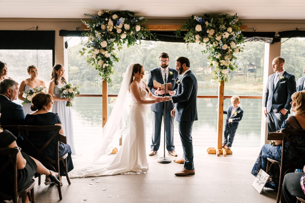 The couple holding each other's hands as they look at each other during their ceremony at Rock Island Lake Club.