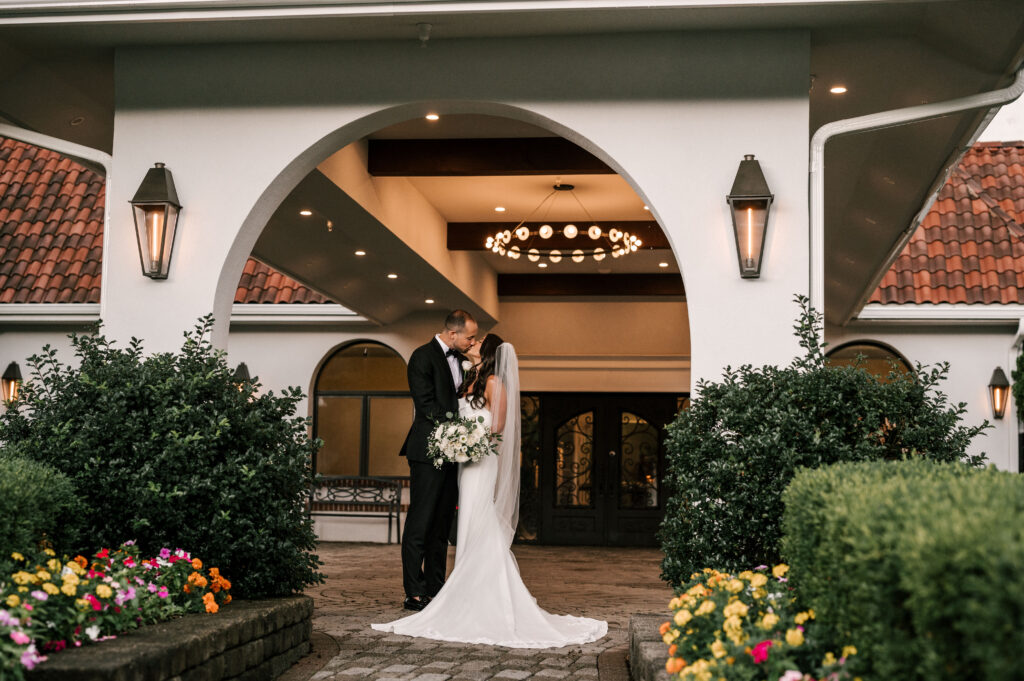 The bride and groom kissing under an archway near the entrance of Perona Farms Reserve.
