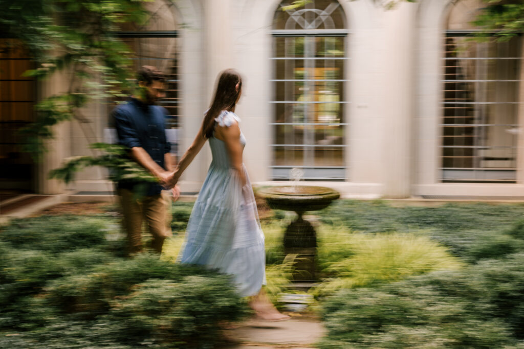 film style photo near a small fountain in a garden during july engagement photoshoot at van vleck house and gardens in nj 