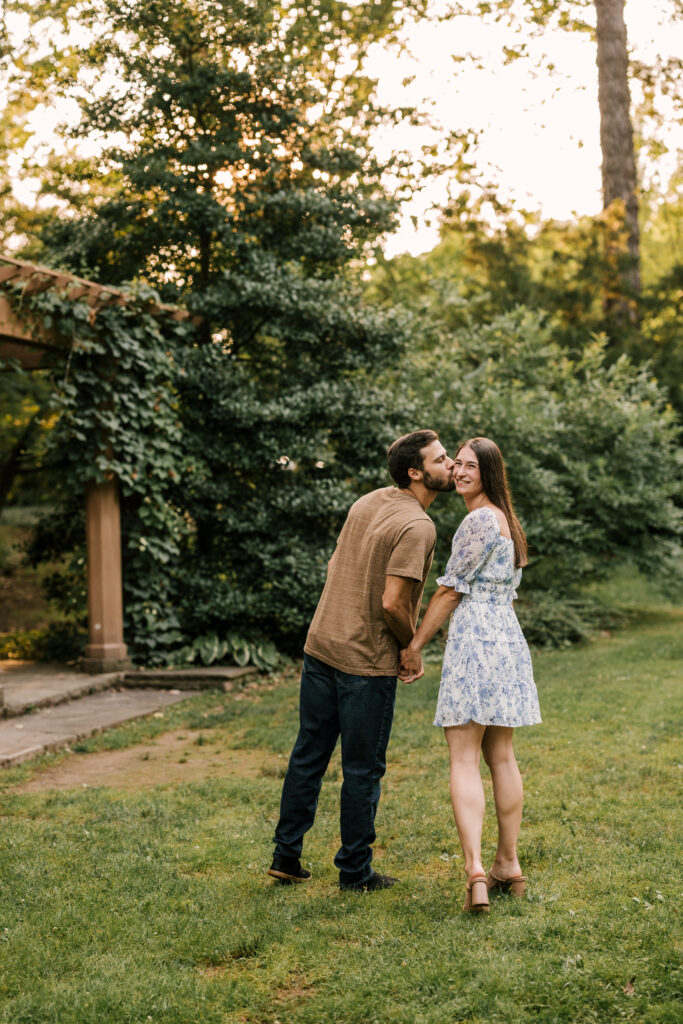 groom to be kissing his bride to be on the cheek - july engagement session