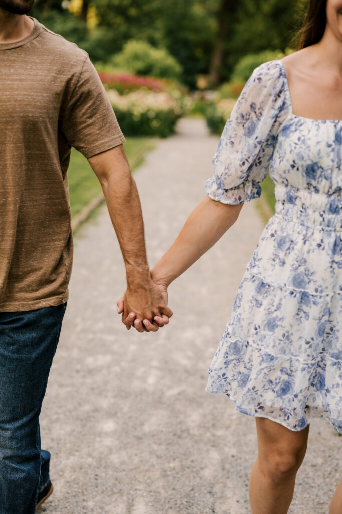 couple holding hands in front of flower field