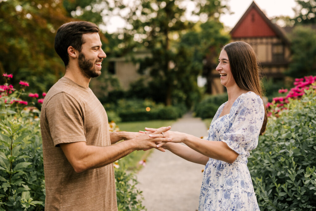 couple laughing in front of florals and historic house at van vleck house and gardens