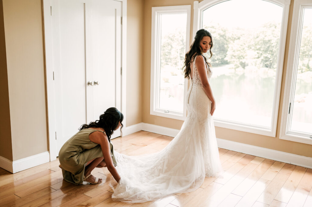 maid of honor helping bride get ready in wedding dress during august nj wedding
