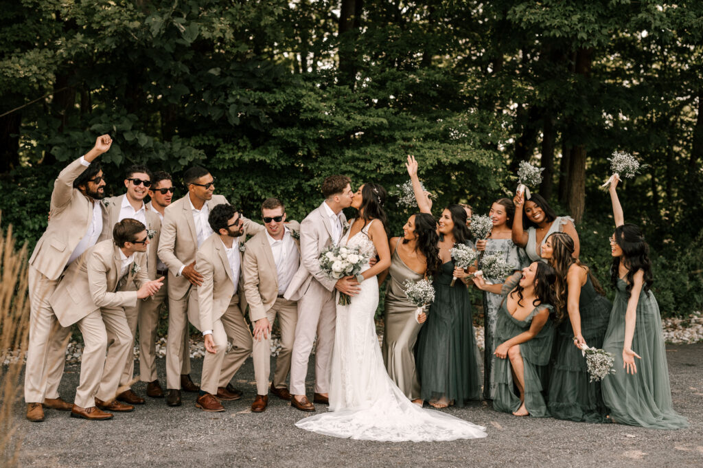 wedding party photo with entire wedding party and bride and groom kissing
