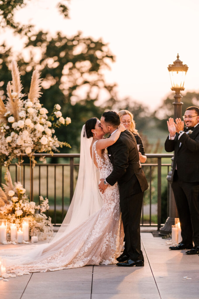 bride and groom share first kiss during sunset ceremony in long island ny wedding