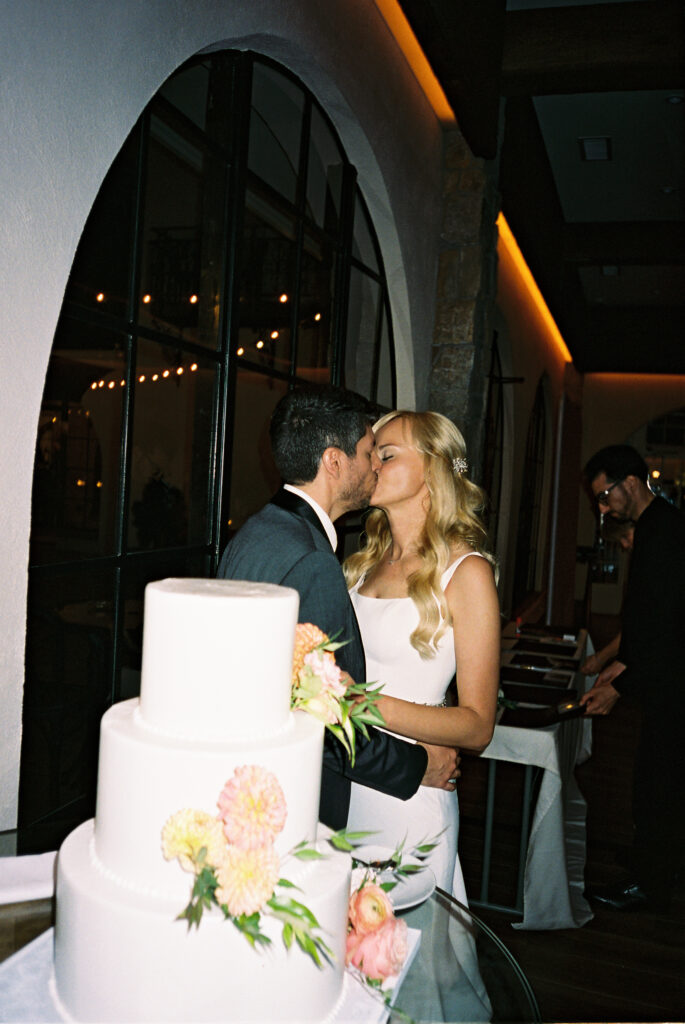 film photo of bride and groom kissing in front of cake during cake cutting at nj wedding in september