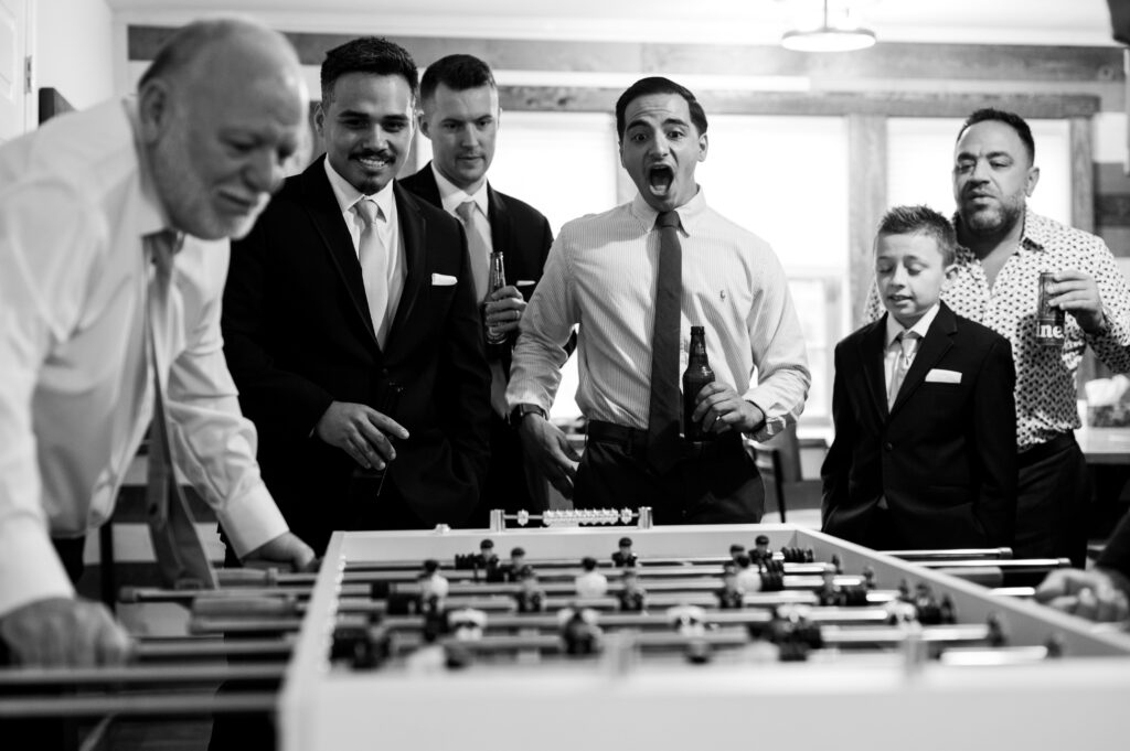 groom and groomsmen passing the time while getting ready by playing foosball at waterloo village
