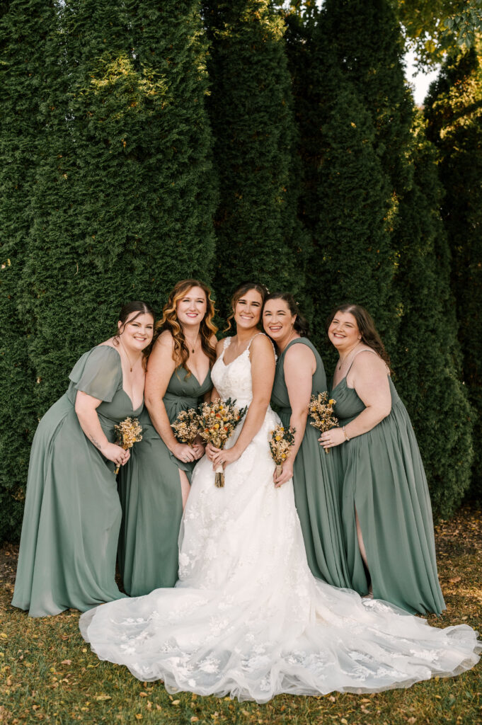 bride and bridesmaids in sage green dresses smiling 