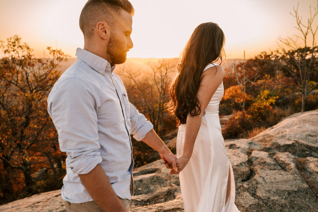 bride to be leading her fiance through the scenic overlook at bear mountain state park in new york during engagement session 