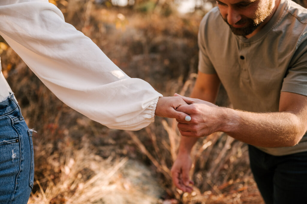 close up of couple holding hands and walking through the fall foliage at bear mountain state park in new york