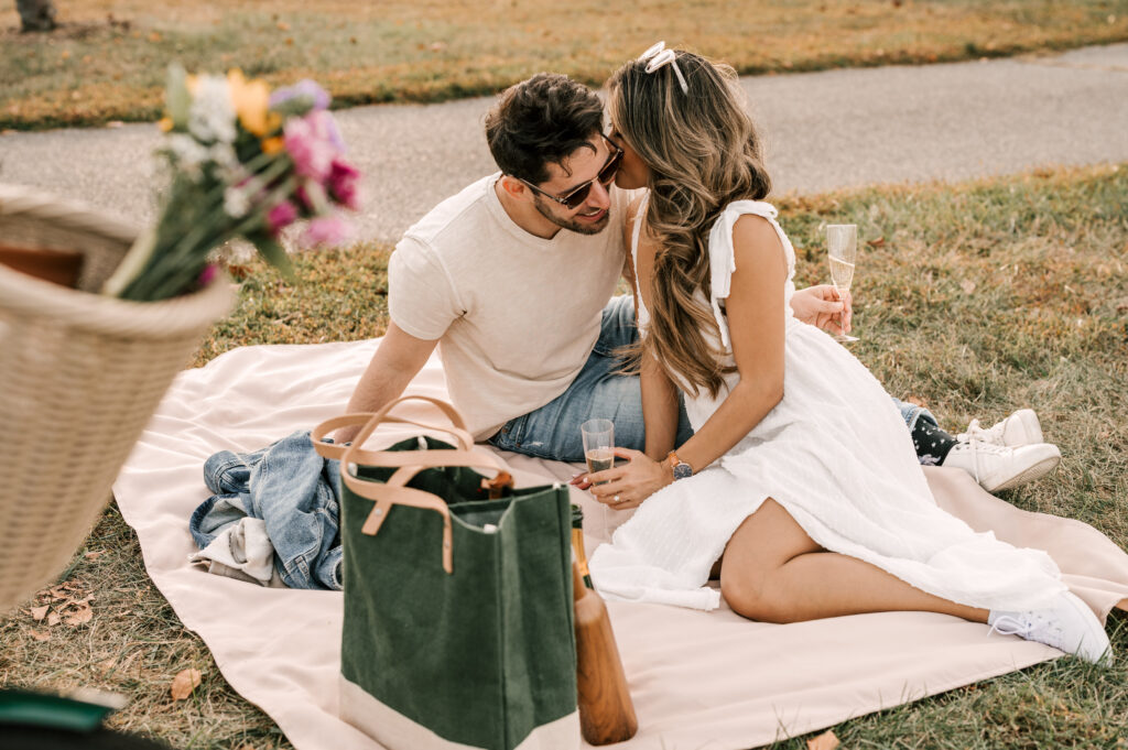 couple sitting on a picnic blanket holding champagne flutes