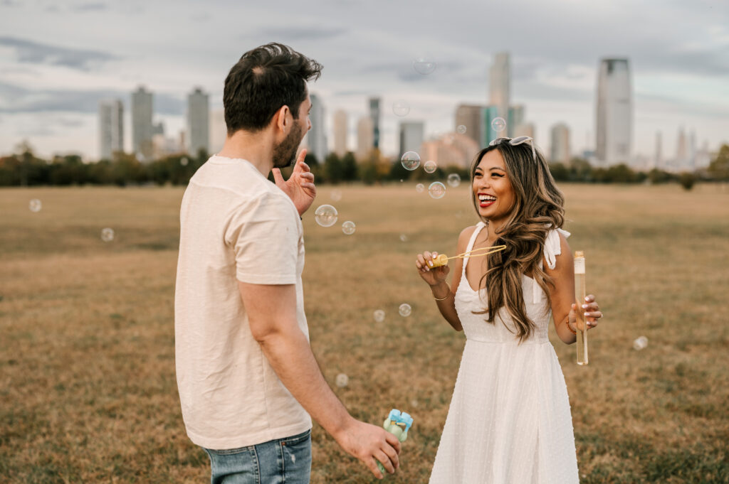 couple playing with bubbles during engagement session with views of new york city in the background
