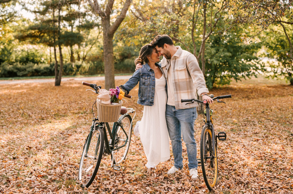 couple sharing a laugh with fall foliage behind them during october engagement session at liberty state park in jersey city