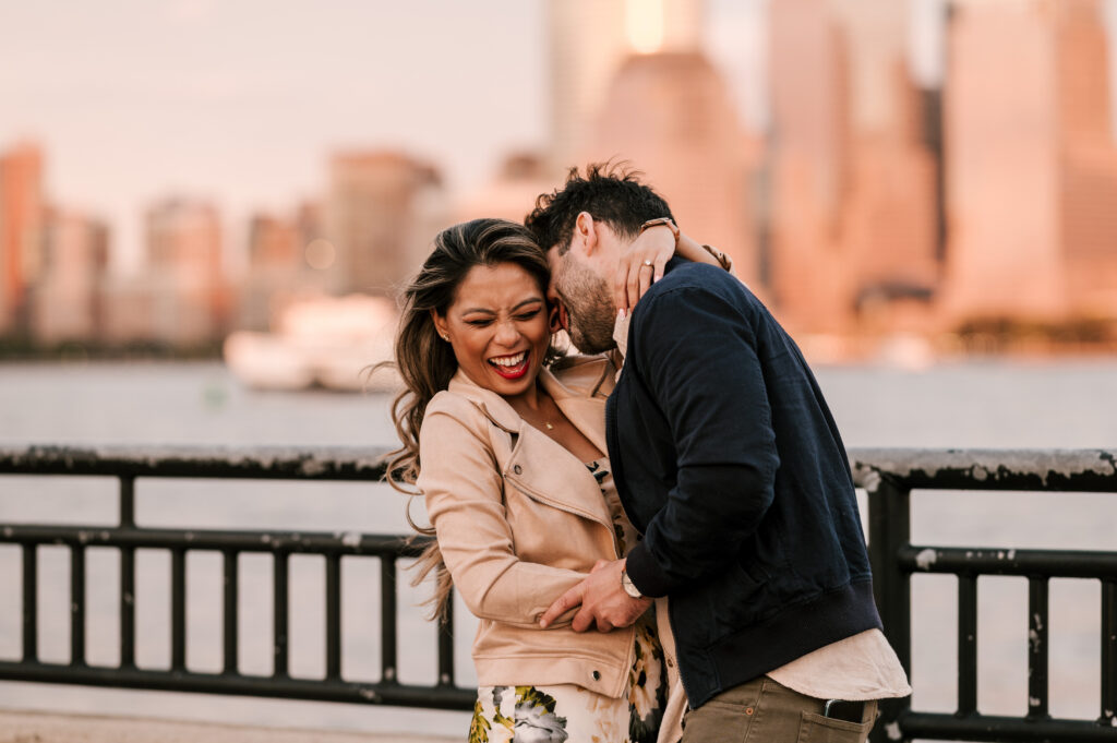 couple laughing and embracing with city skyline in background during october engagement session