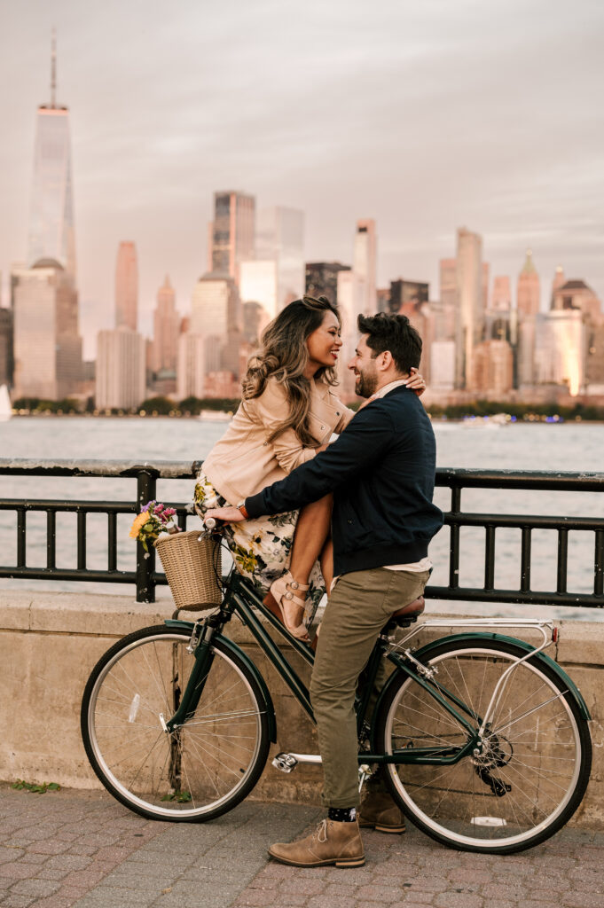 couple sitting on a bike with the new york city skyline behind them during october engagement session