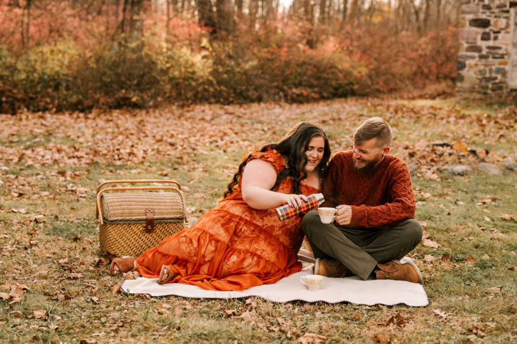couple sharing hot cocoa during a fun picnic at their november engagement session in new jersey