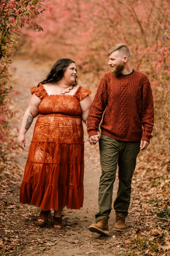 couple holding hands in a wooded area during november engagement session at long wood ironworks state park in nj 