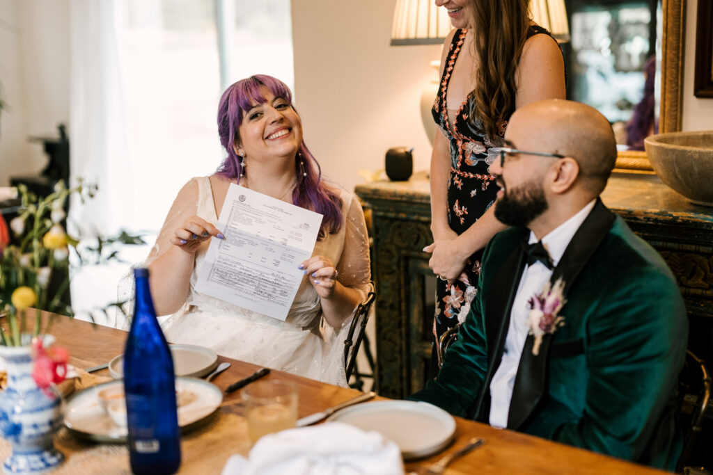 bride smiling and holding up marriage license after wedding in new york