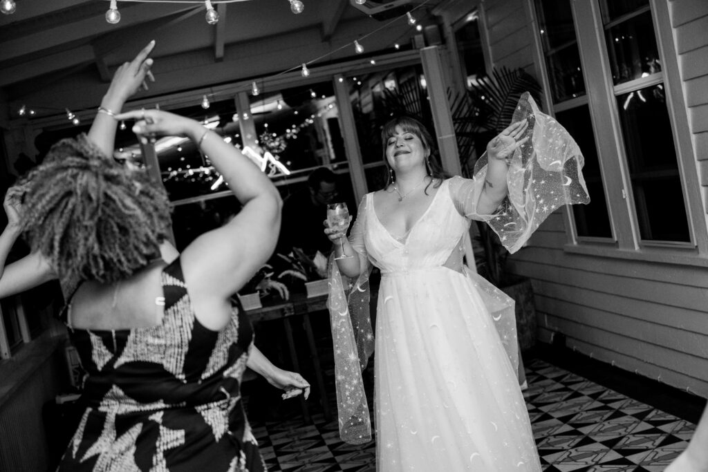 bride in wedding gown with moon & star details dancing with friends at the end of the night