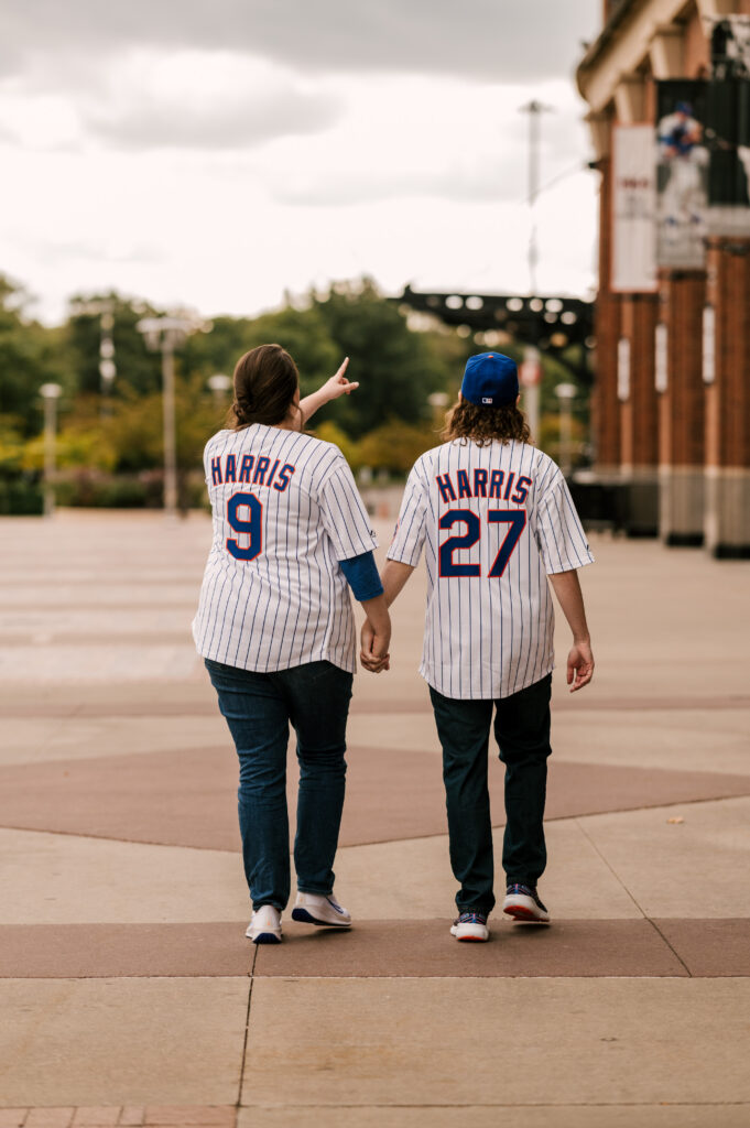 couple in Mets jerseys walking around Citi Field during September engagement session