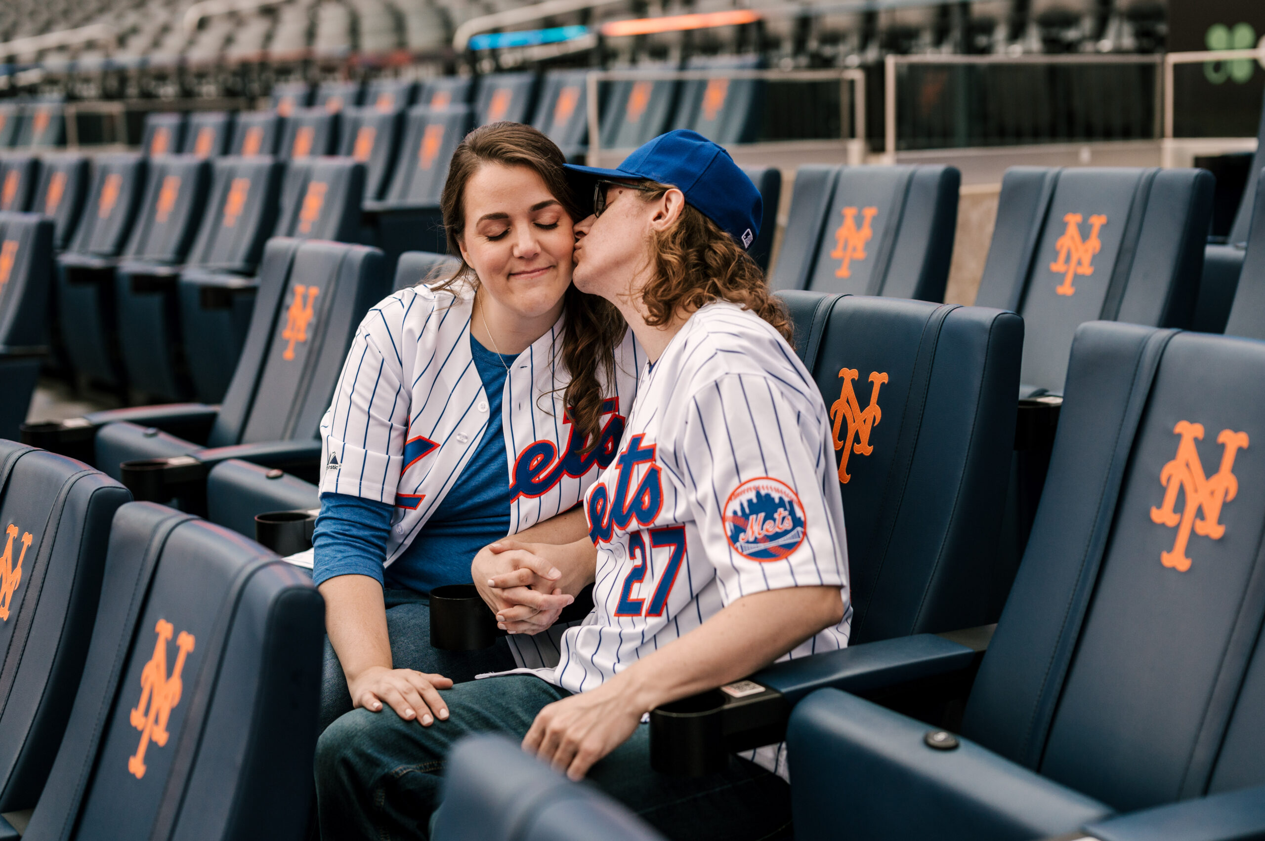 couple sitting in the stadium seats at Citi Field during engagement session