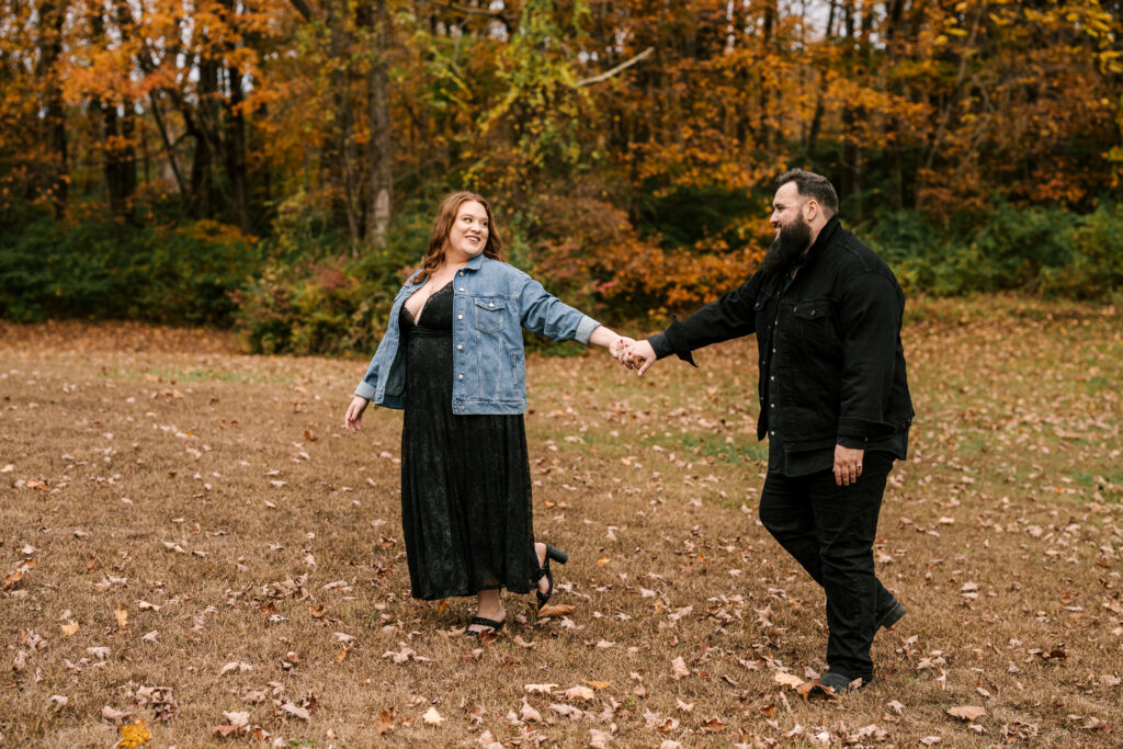 couple laughs and walks along fall foliage at Ringwood Manor