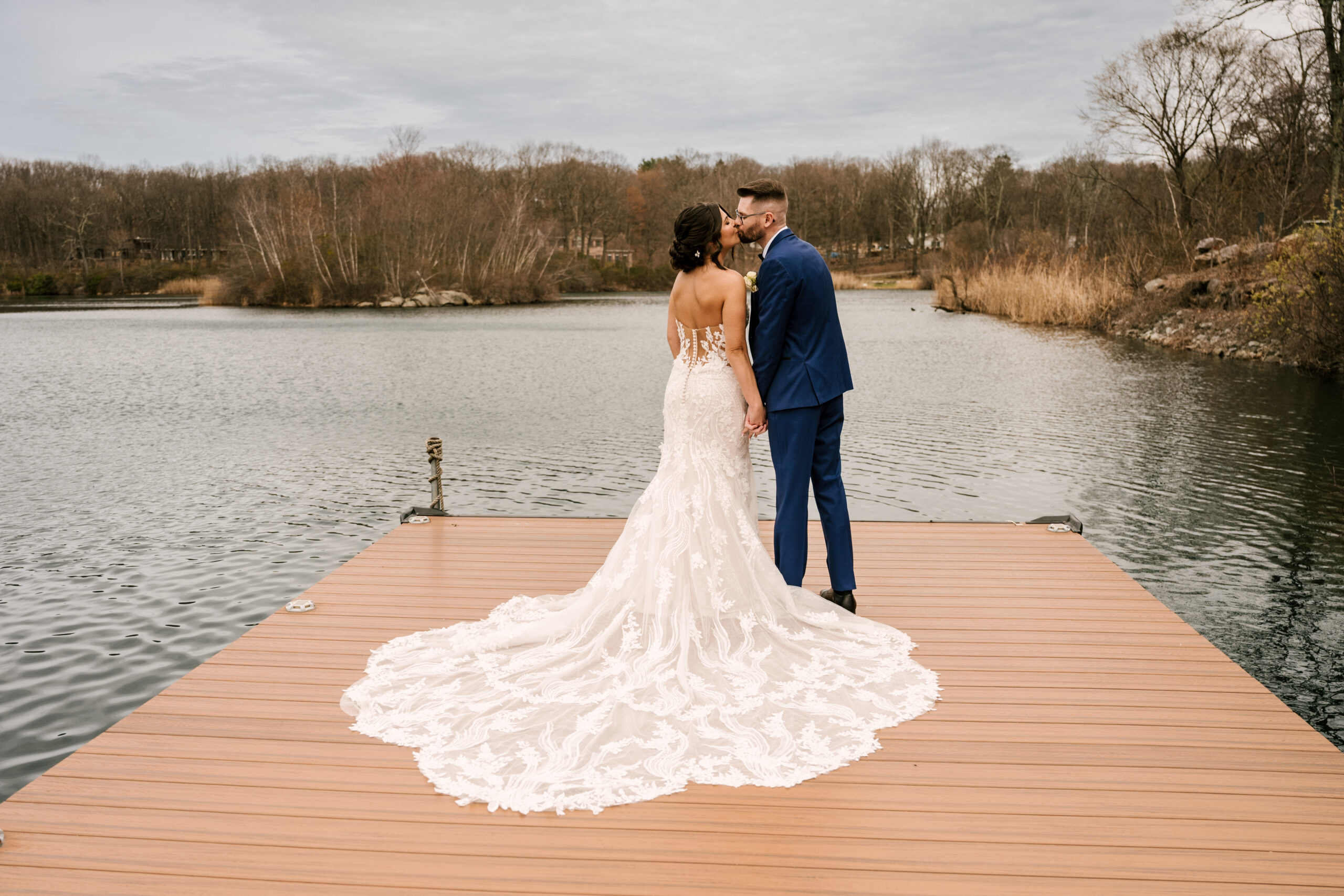 Bride and groom kiss on the dock by the lake at Rock Island lake club for their wedding in sparta NJ