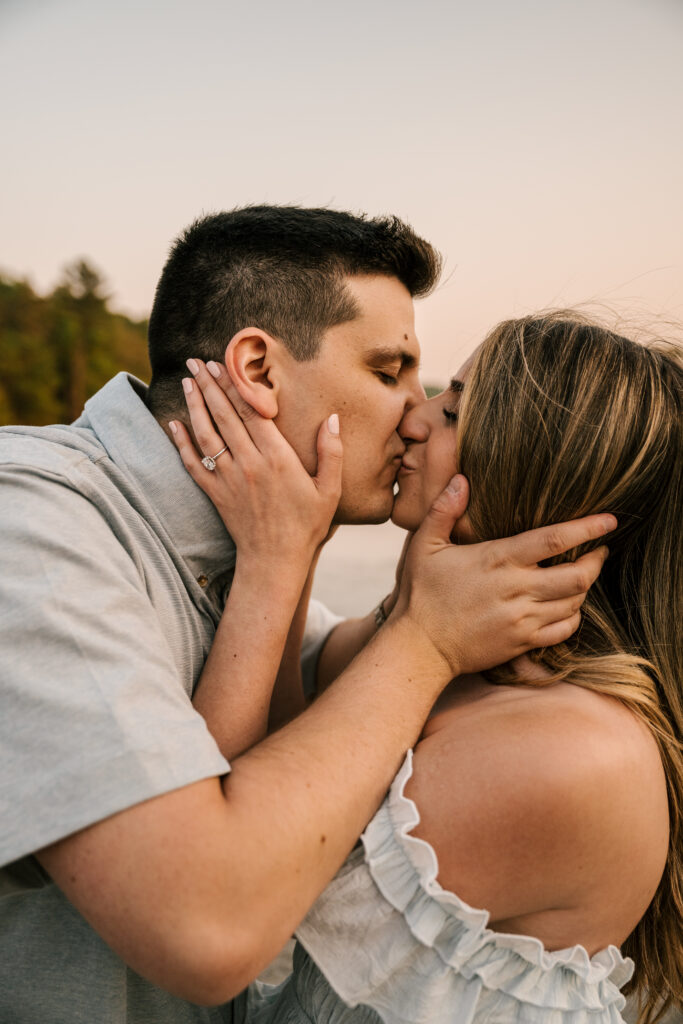 close up of couple grabbing each other's faces and kissing during nj engagement session at wawayanda state park