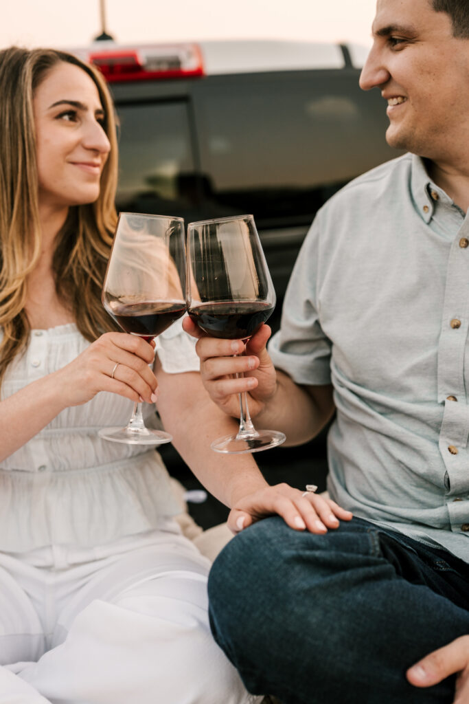 couple clinking wine glasses together during engagement session at wawayanda state park