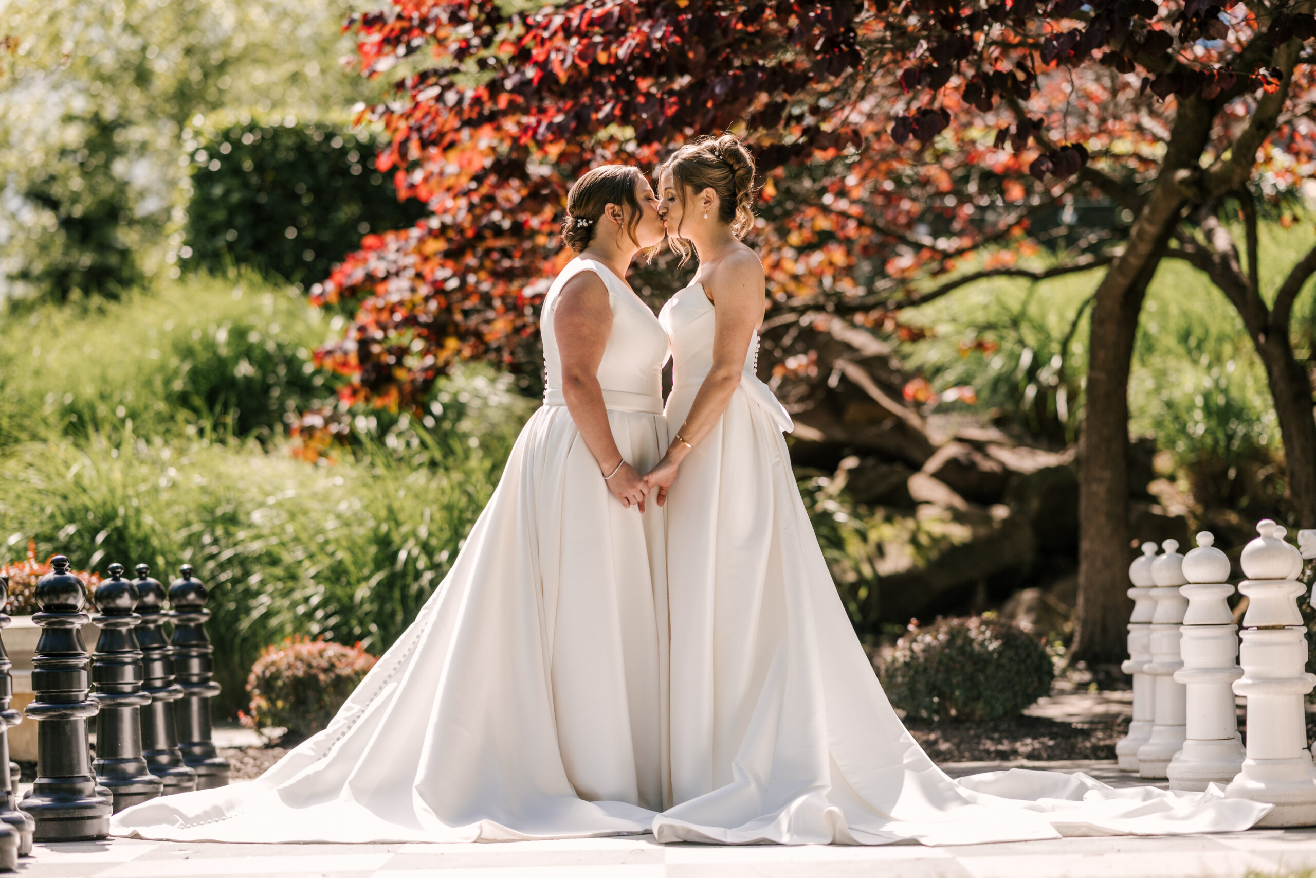 brides kissing on chess board in courtyard of stonehouse at stirling ridge same sex wedding in warren, nj. lgbtqia+ friendly