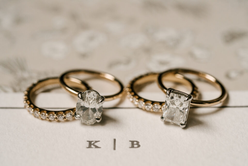 close up detail of both brides' wedding bands and engagement rings