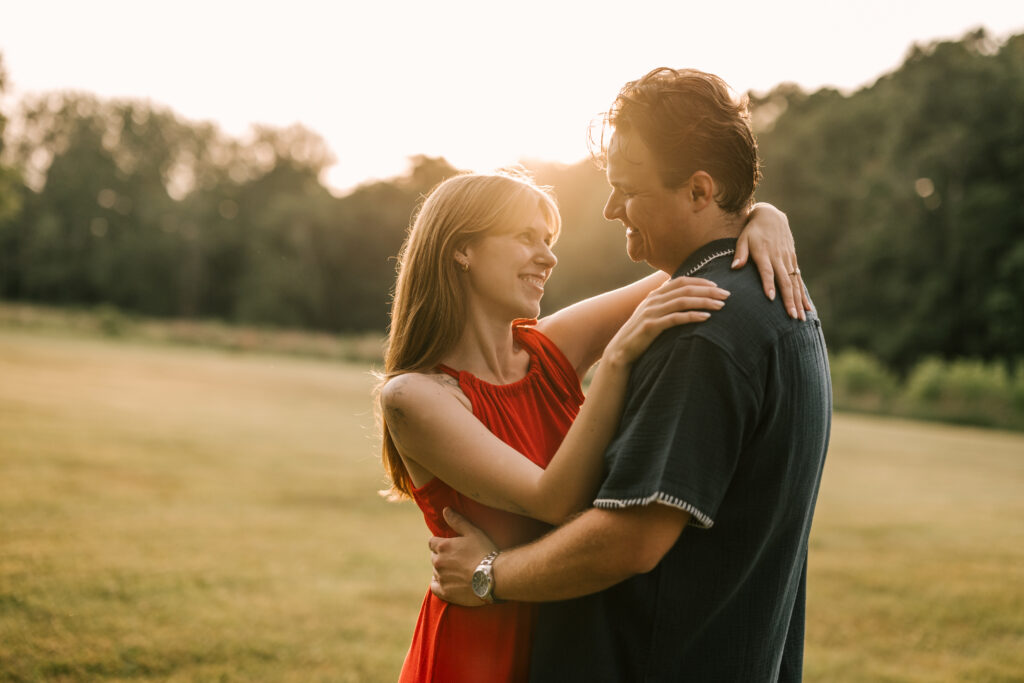 Engaged couple embraces in the field during sunset at Natirar in Peapack, Gladstone NJ for their June engagement session.