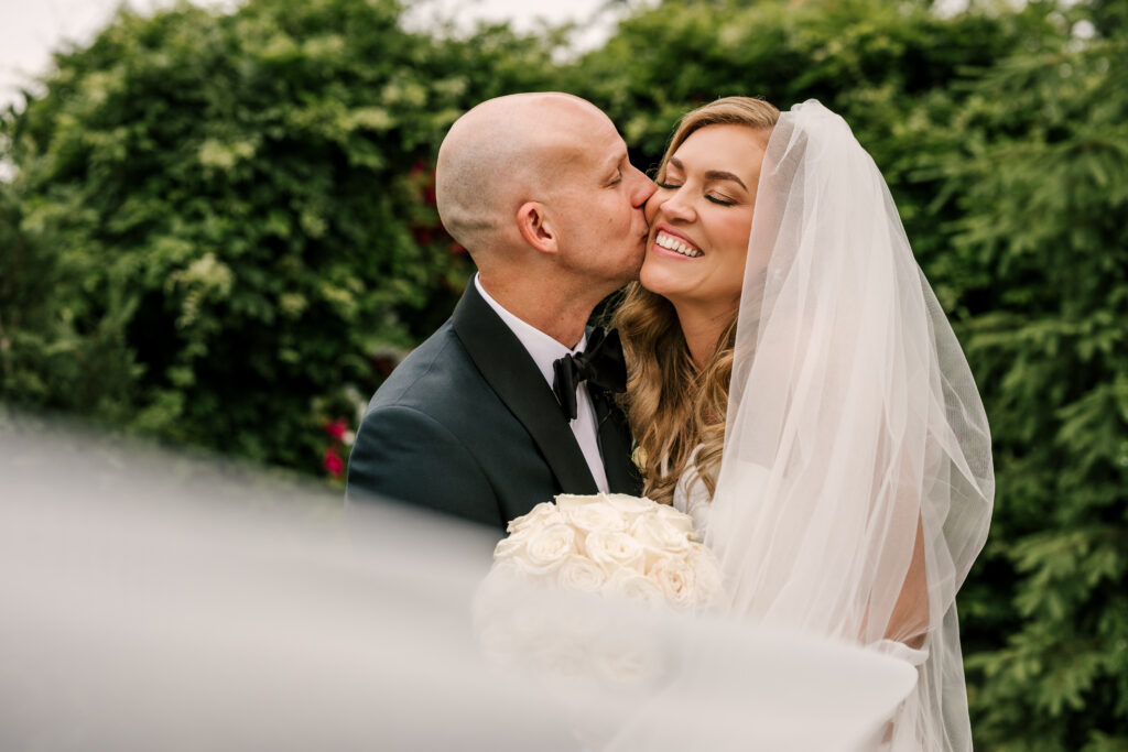 groom kissing bride on the cheek during their june wedding at park loft